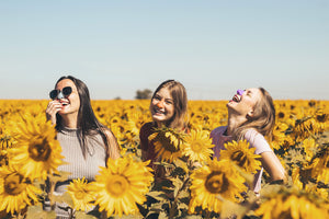 3 girls wearing fun, colorful Nöz Sunscreen in a sunflower field